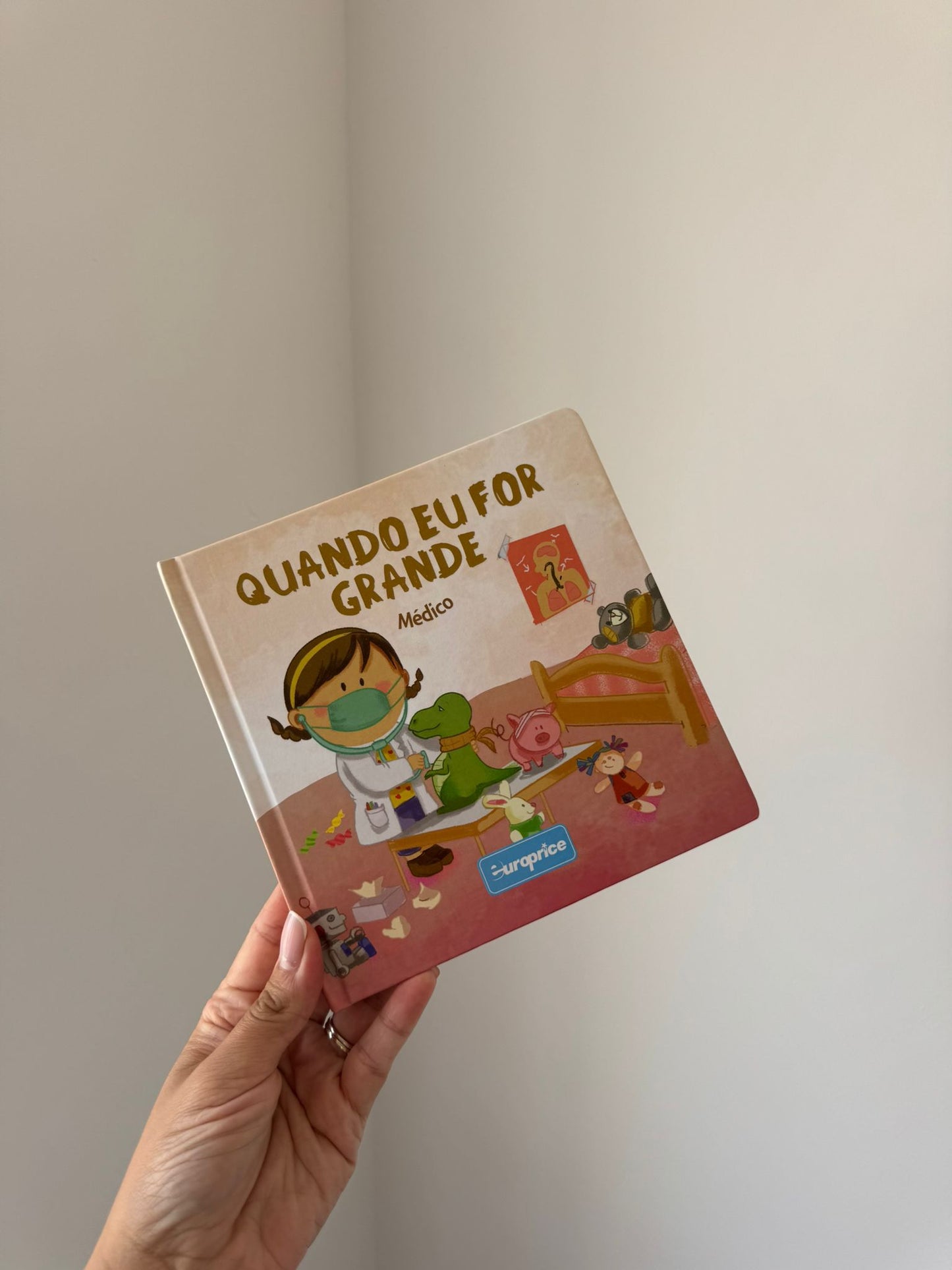 Children's book titled 'Quando Eu For Grande' held by a hand against a plain background